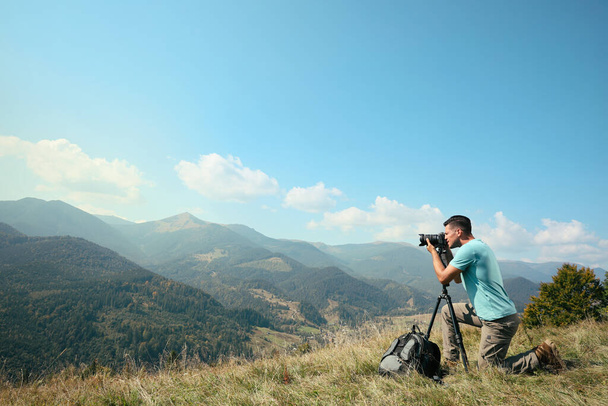 Professional photographer taking picture with modern camera in mountains. Space for text - Фото, зображення