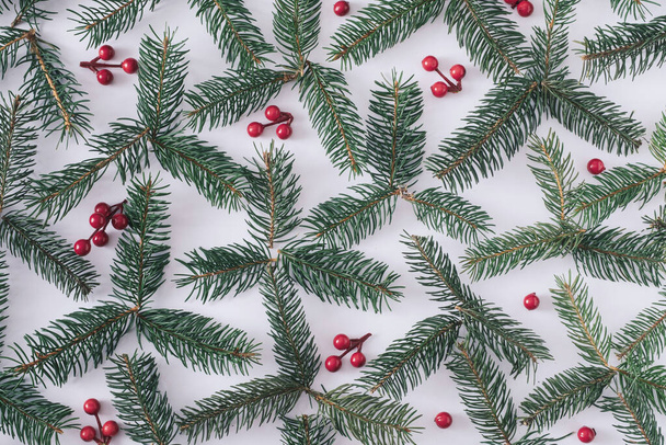Christmas holiday background of pine branches with red berries arranged as a decorative flat lay still life on white in a full frame view - Fotoğraf, Görsel
