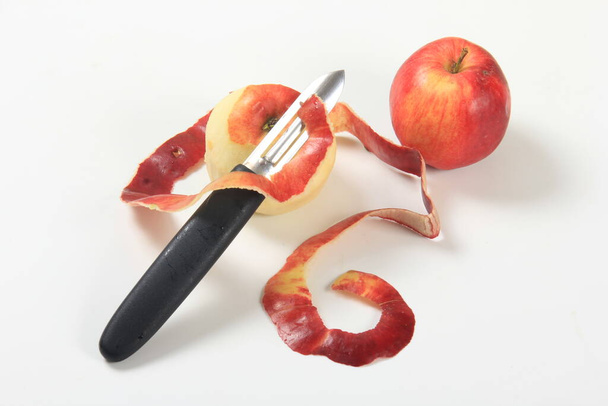 Beyaz arka planda elma kabuğu, bıçak ve kırmızı elmalar - Fotoğraf, Görsel
