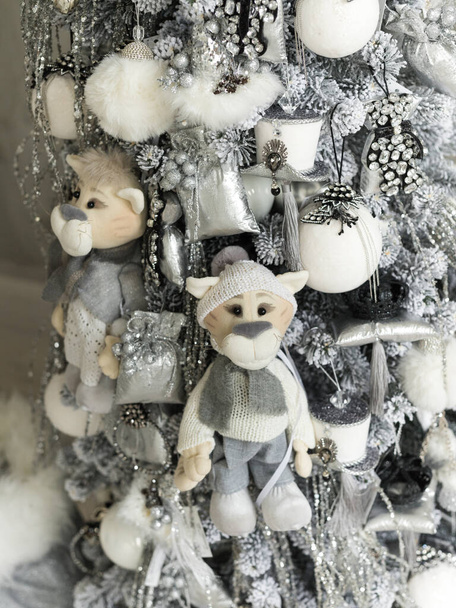 Nahaufnahme eines grau-weißen Weihnachtsbaums mit weichen Tigern, Schmuckspielzeug und Girlanden - Foto, Bild