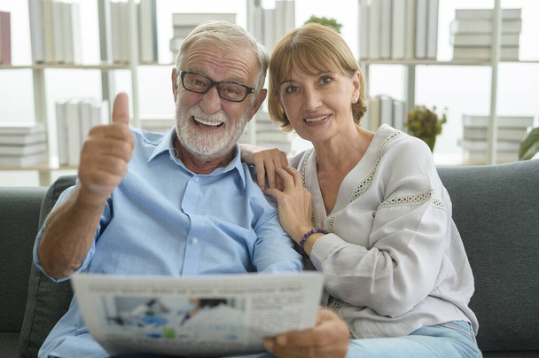 Glückliches Paar kaukasische Senioren entspannen sich und lesen Zeitung im Wohnzimmer  - Foto, Bild