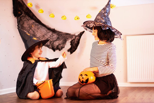 Halloween kids. A boy and a girl celebrate the holiday and share the sweets - Photo, Image