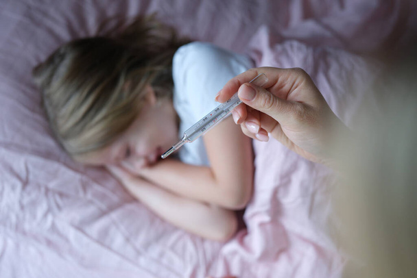 Mutter misst Temperatur ihrer Töchter vor dem Schlafengehen - Foto, Bild