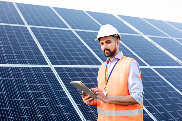 Engineer with a tablet stands on the background of a solar station - Foto, Bild