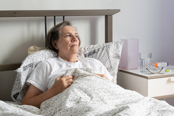 senior woman female in bed home closeup sick tired flat unhappy. - Zdjęcie, obraz