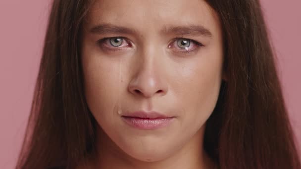 Tyytymätön nainen itkee katsoen kameran pyyhkimällä kyyneleitä surullinen kasvot poseeraa yli vaaleanpunainen Studio tausta. Suru ja turhautuminen, negatiiviset tunteet. Rajattu laukaus - Materiaali, video