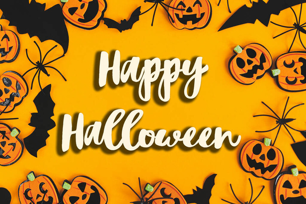 Boldog Halloween szöveges jel sütőtök, jack o lámpások, pókok, denevérek keret lapos feküdt narancssárga háttér. A szezon üdvözlőlapja. Kézzel írt boldog halloween szöveg. Csokit vagy csalunk - Fotó, kép