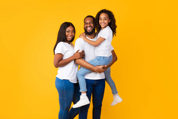 Feliz hombre negro posando con esposa e hija sonriente - Foto, imagen