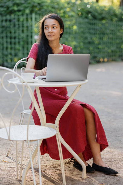 beautiful and young millennial african woman in a public place working on a laptop - Foto, Bild