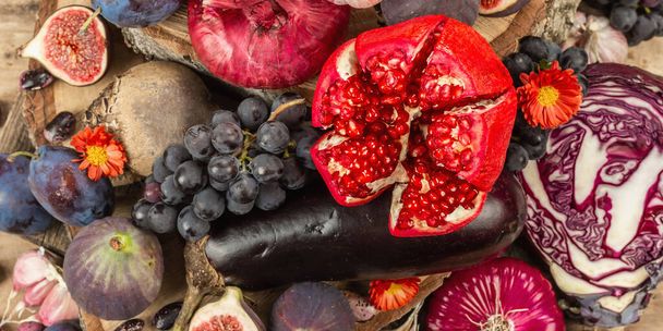 Blue, red and purple food. Culinary background of fruits and vegetables. Fresh figs, plums, onion, eggplant, grape, cabbage, apple, garlic, dogwood, pomegranate, beetroot. Wooden stands and old boards - Photo, Image