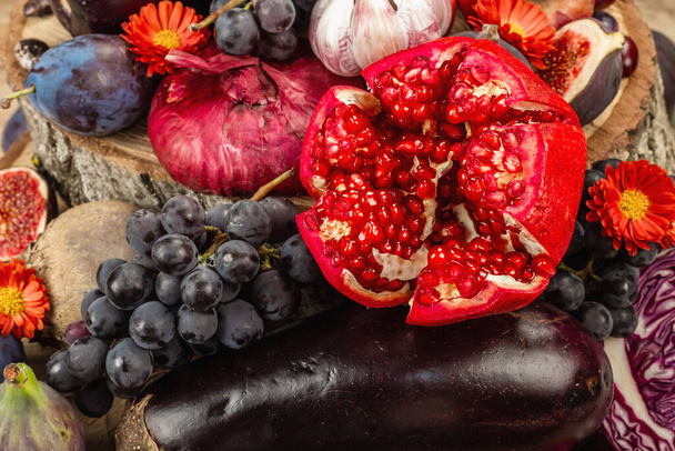 Blue, red and purple food. Culinary background of fruits and vegetables. Fresh figs, plums, onion, eggplant, grape, cabbage, apple, garlic, dogwood, pomegranate, beetroot. Wooden stands and old boards - Photo, Image