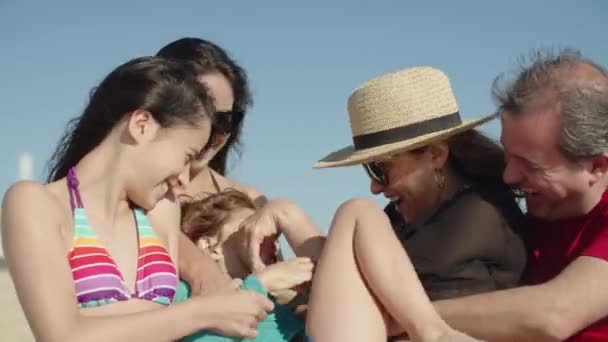 Feliz familia sosteniendo niño en brazos y cosquillas su en el día de verano  - Metraje, vídeo