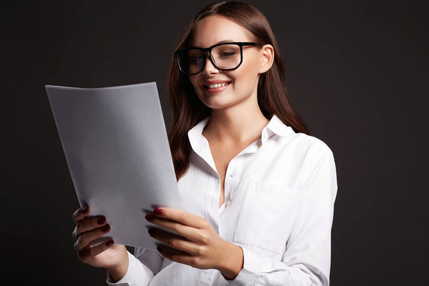 gyönyörű mosolygós nő szemüvegben, aki dokumentumokat néz. portré üzletasszonyról - Fotó, kép