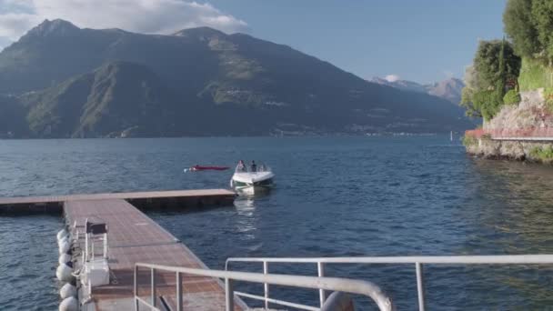 Dalekie ujęcie: Manewr motorówką nad jeziorem Como, w małym porcie Warenny - Materiał filmowy, wideo