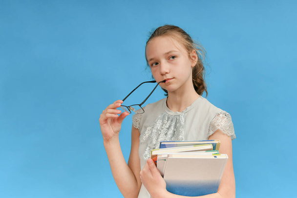 Dívka drží brýle v jedné ruce, učebnice v druhé. - Fotografie, Obrázek