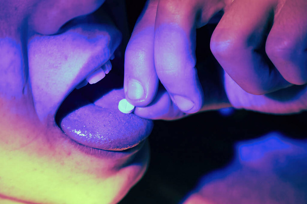 Guy teenager takes drugs pills in a night dance club. Child addiction concept. - Foto, Imagem