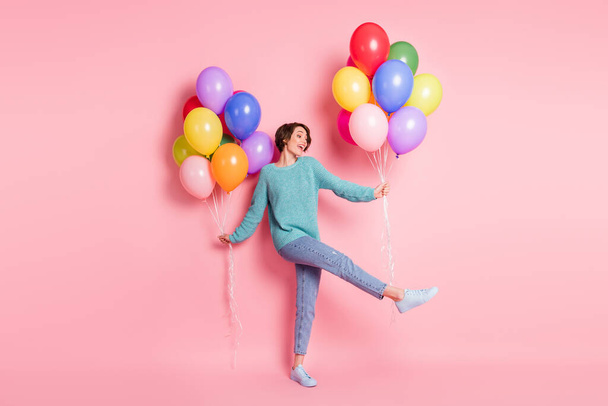 Full size photo of adorable charming positive young girl hold balloons look empty space isolated on pink color background - Foto, Bild