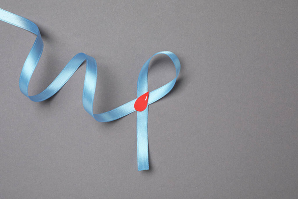 Light blue ribbon with paper blood drop on grey background, top view and space for text. Diabetes awareness - Foto, imagen