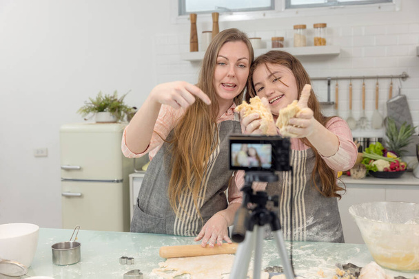 Egy élő digitális fényképezőgép a konyhában, anya és lánya mosolyog, és érezd jól magad, miközben elkészíti keksz tészta együtt, lánya tanul, hogyan kell sütit csinálni az anyjával. - Fotó, kép