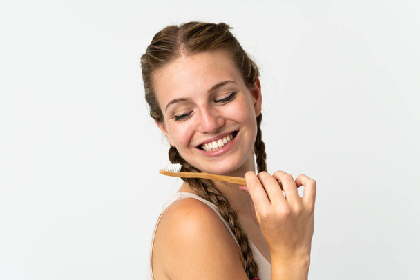 Mujer joven caucásica aislada sobre fondo blanco con un cepillo de dientes y expresión feliz - Foto, Imagen