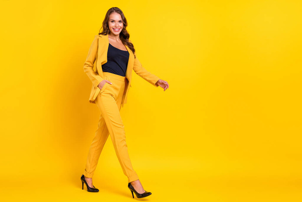 Photo of beautiful charming young lady wear suit jacket buying empty space walking smiling isolated yellow color background - Foto, imagen