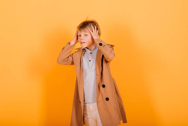 Grimacing emotional redhead fasion boy posing in a yellow studio - Fotoğraf, Görsel
