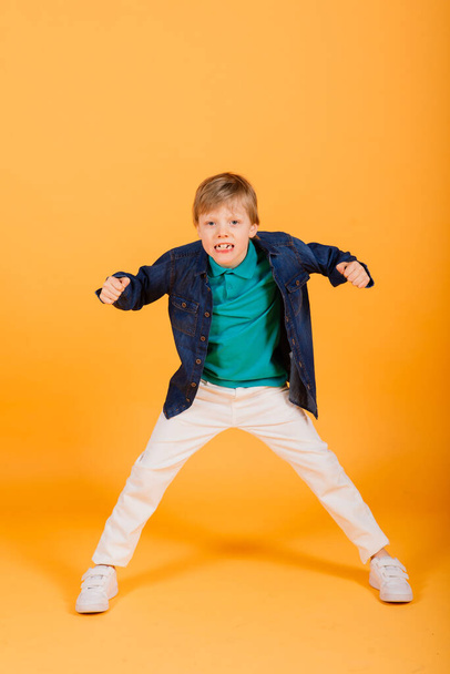 Grimaszoló érzelmi vörös hajú fasion fiú pózol egy sárga stúdióban - Fotó, kép