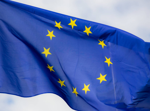 Официальный флаг Европейского Союза перед голубым небом. - Фото, изображение