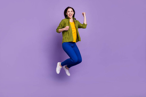 Full size profile side photo of young girl happy positive smile winner success ecstatic fists hands jump isolated over violet color background - Foto, Imagem
