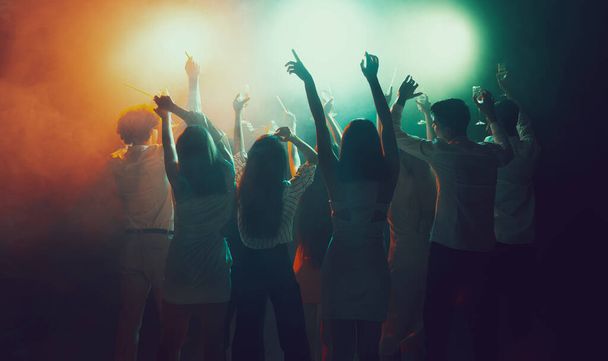 Grupa młodych, aktywnych ludzi w klubie nocnym, imprezowicze tańczący w neonach - Zdjęcie, obraz