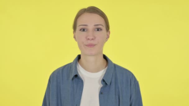 黄色の背景に頭を振ることによって兆候を示さない若い女性  - 映像、動画