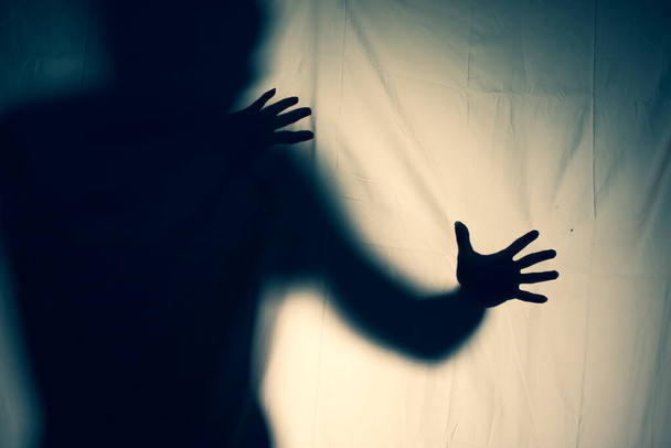 frightening ghost in a white sheet nightmare. scary picture of hands behind curtain. halloween idea - Фото, зображення