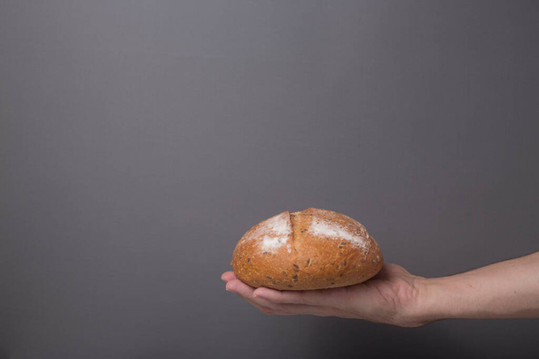 loaf of bread on a man's hand isolated on gray background close up - Fotó, kép