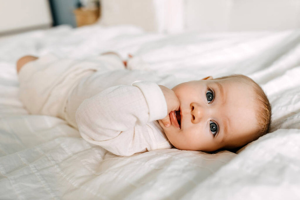 Pět měsíců staré dítě ležící v posteli, sající prsty. - Fotografie, Obrázek