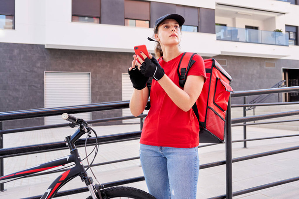 Een fietser levering meisje met behulp van smart phone op straat - Foto, afbeelding