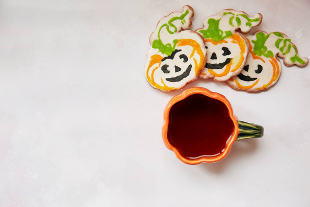 Halloween creative concept background: pumpkin cup and homemade cookies in shape of cute pumpkins. Copy space. Aesthetic autumn mood or trick or treat concept. Autumn decorations. - Photo, Image