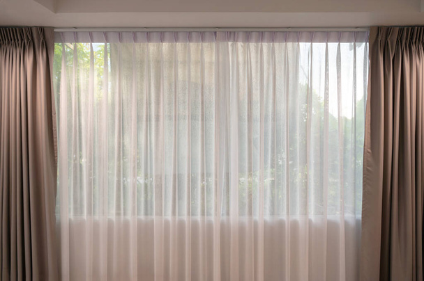 Відкрита бежева завіса зі світлофільтровою тканиною на вікні вдома
 - Фото, зображення
