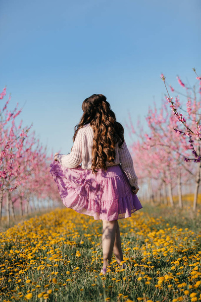 Девушка в шляпе. Девушка закрыла лицо шляпой. Весной девочка гуляет по саду. Цветущий сад. - Фото, изображение