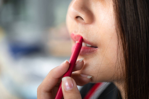 Close-up Beautiful asian woman applying red lipstick pencil on her lips - Fotoğraf, Görsel