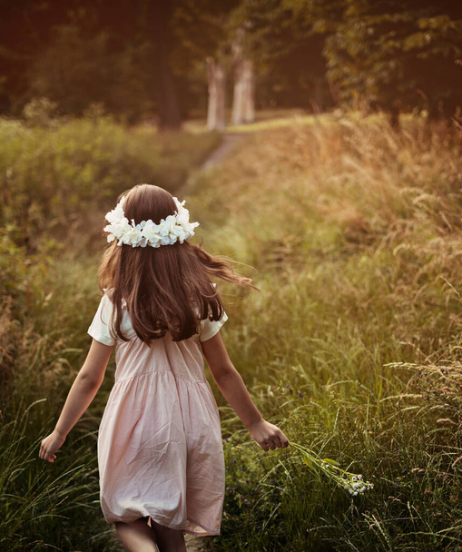 Portrait of cute kid girl with bloom flowers. Nature outdoor. Child in nature concept. - Фото, изображение