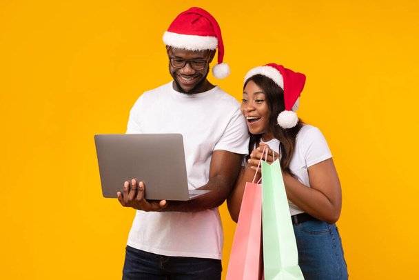 African Couple Compras en línea con el ordenador portátil Comprar regalos de Navidad, Estudio - Foto, imagen