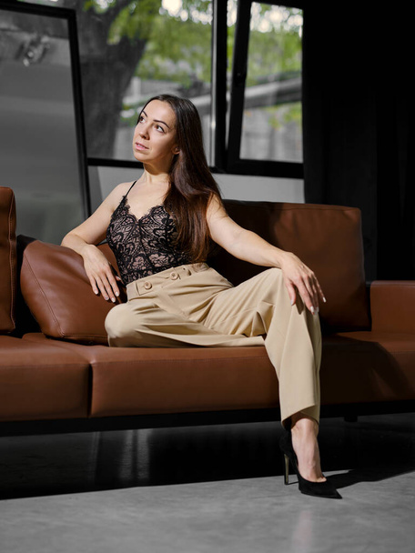 Middle age woman sitting on leather sofa and looking to the side - Foto, immagini