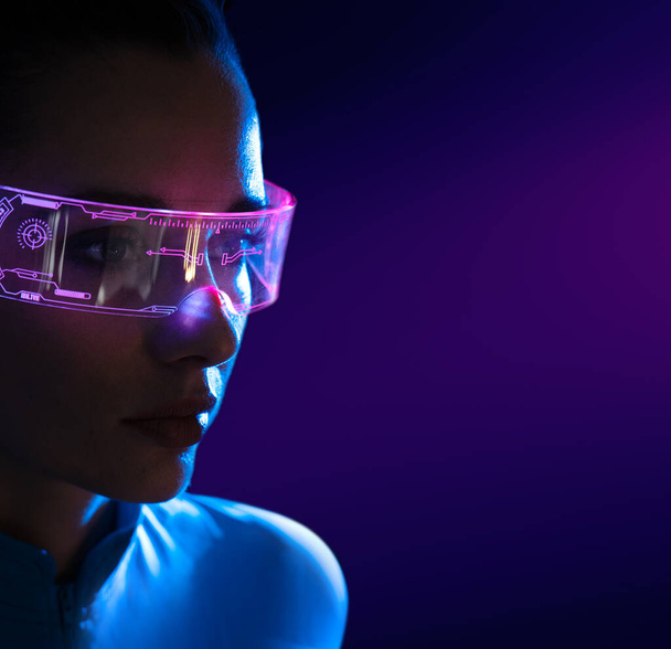 Concept of future technology or entertainment system, virtual reality. Female portrait lit by HUD interface - Foto, afbeelding
