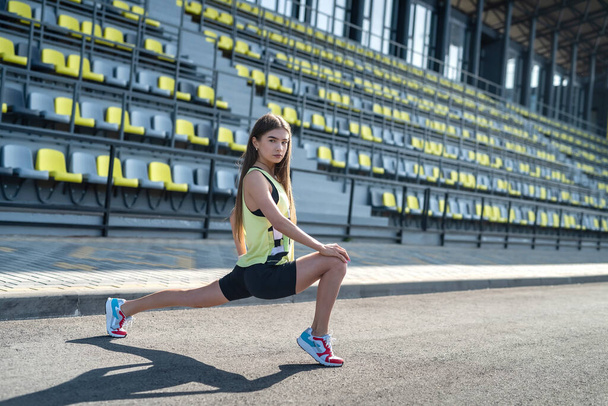 Atleta feminina fazendo exercícios de alongamento manhã no estádio. conceito de esporte para a vida em saúde - Foto, Imagem