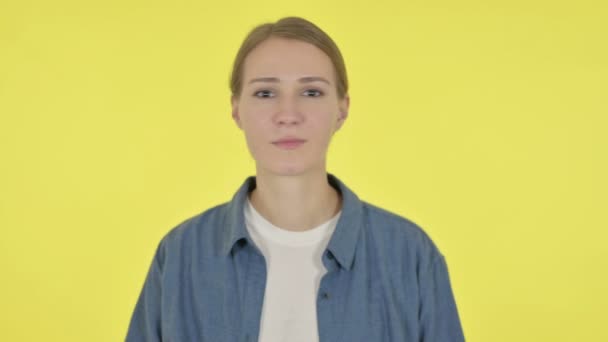 Mujer joven que no muestra ningún signo por gesto de brazo sobre fondo amarillo  - Imágenes, Vídeo