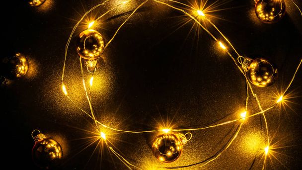 Karácsonyi fények határán. Arany fény koszorú dekoráció, arany izzó elszigetelt fekete karácsonyi party dísz dekoráció háttér. Ragyogó fények a karácsonyi szünetben - Fotó, kép