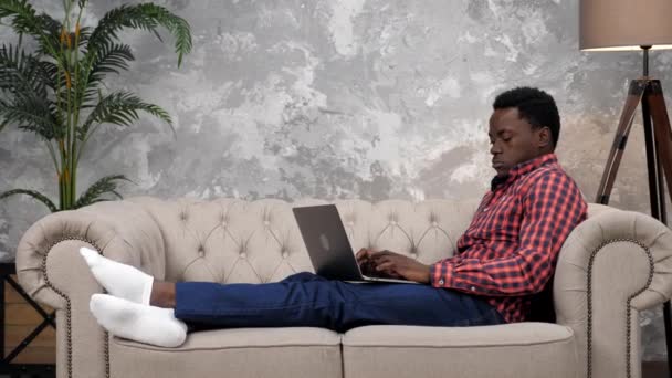 Empresario afroamericano trabaja portátil en línea charlando con los empleados de la empresa - Metraje, vídeo