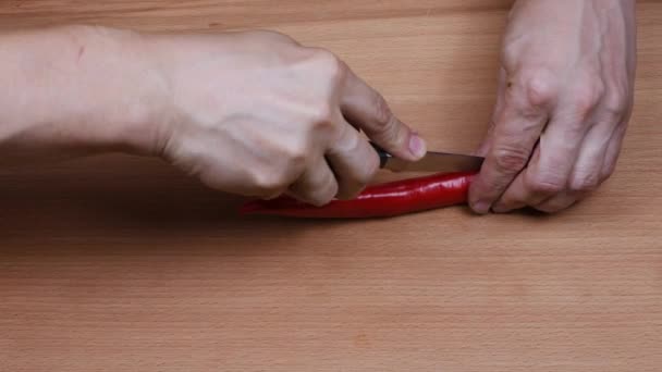 De man snijdt rode chili pepers. Zijaanzicht. 4K UHD-videobeelden 3840X2160. - Video