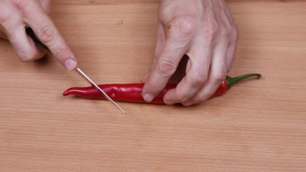 A fickó vörös chilis paprikát vág. Oldalnézetből. 4K UHD videó felvétel 3840X2160. - Felvétel, videó