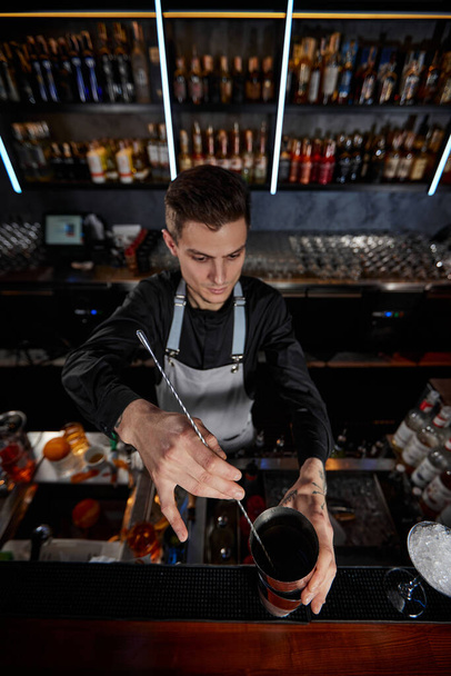 Barman stirring cocktail in shaker with spoon - Foto, imagen